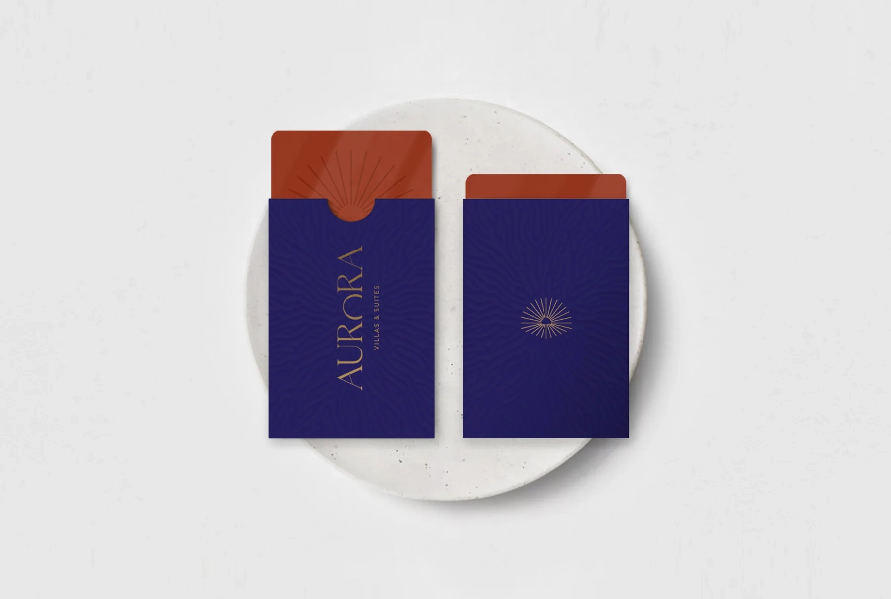 Aurora room key and sleeve mockups using purple, terracotta, gold lettering, and the sun motif
